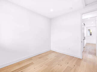 Step into this bright and airy room, featuring pristine white walls and a beautiful light wood floor that creates a warm and inviting atmosphere.