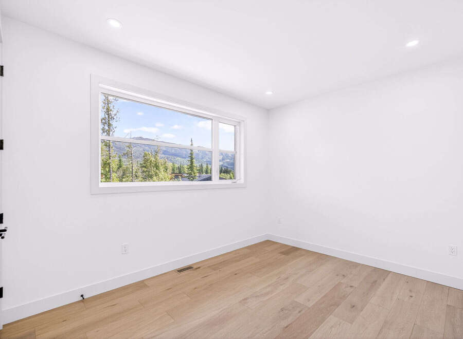 Experience breathtaking mountain views from this stunning bedroom, featuring a large picture window that floods the space with natural light.