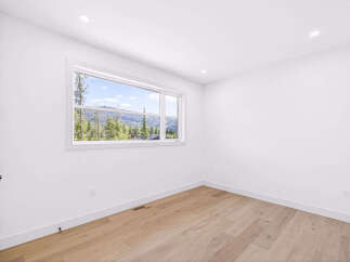 Experience breathtaking mountain views from this stunning bedroom, featuring a large picture window that floods the space with natural light.