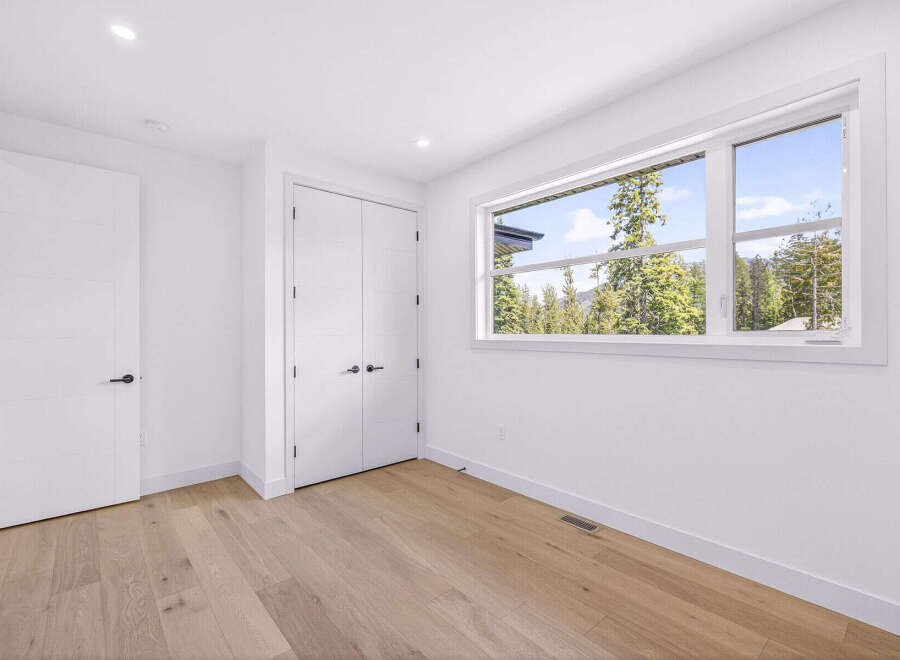 Step into this bright and airy room, featuring a large window that floods the space with natural light and offers stunning views of the surrounding evergreen forest and mountains.