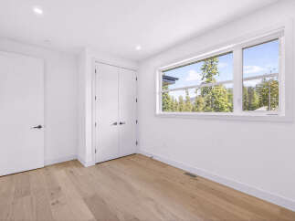 Step into this bright and airy room, featuring a large window that floods the space with natural light and offers stunning views of the surrounding evergreen forest and mountains.