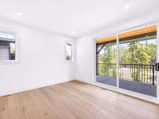 Step into this bright and airy bedroom, featuring a large sliding glass door that opens to a scenic balcony with stunning mountain and forest views.