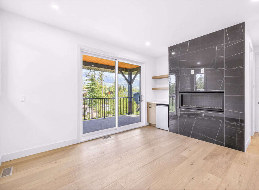Experience modern living with this stunning room featuring a sleek, black marble fireplace as the centerpiece.