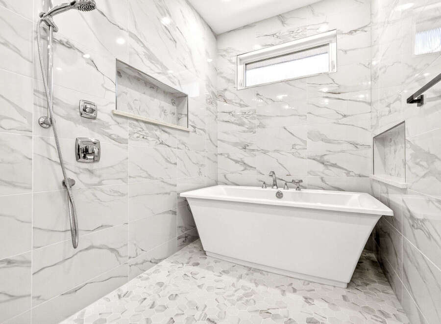 Experience modern luxury in this stunning bathroom, featuring a sleek freestanding bathtub and a separate rainfall shower.