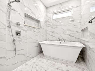 Experience modern luxury in this stunning bathroom, featuring a sleek freestanding bathtub and a separate rainfall shower.