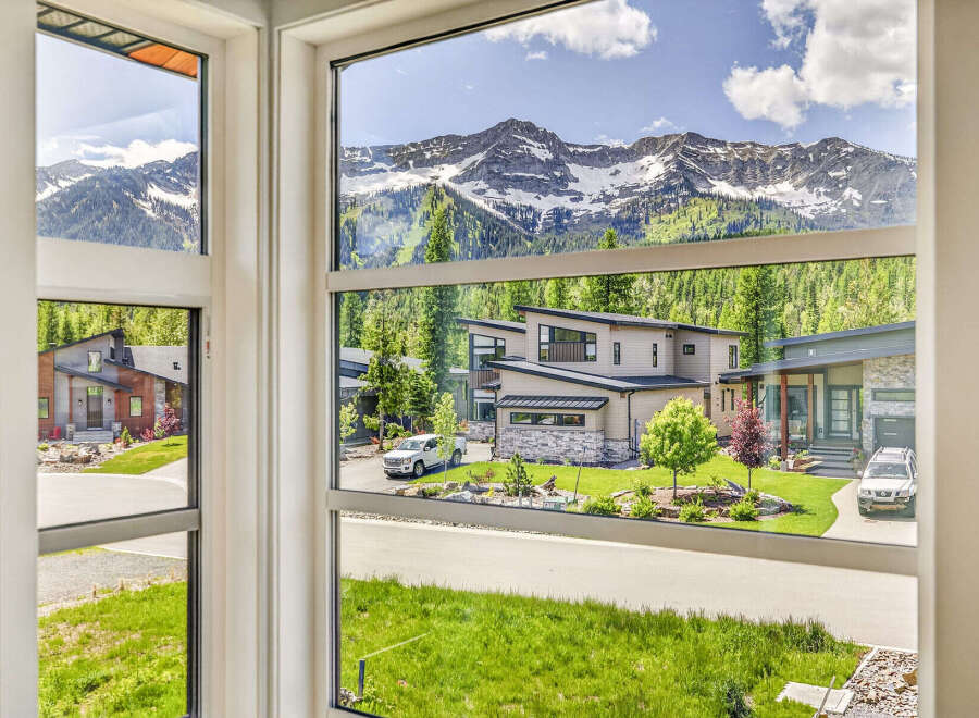 Experience luxury mountain living in this stunning modern home, boasting breathtaking panoramic views of snow-capped peaks and lush green forests.