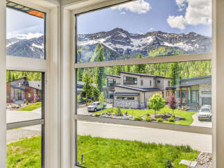 Experience luxury mountain living in this stunning modern home, boasting breathtaking panoramic views of snow-capped peaks and lush green forests.