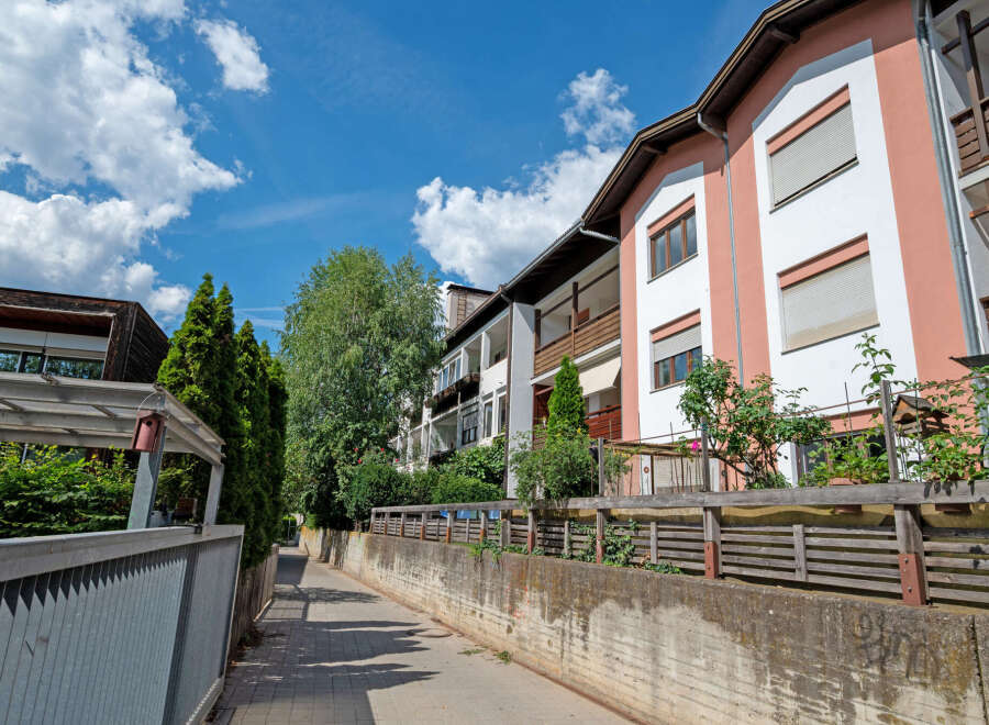 Discover modern living in this charming apartment complex, featuring a vibrant facade with pink and white accents.