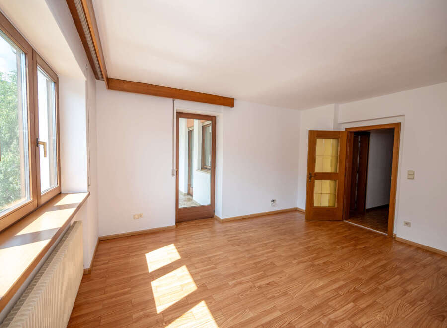 This spacious room features a large wooden-framed window with a wide windowsill, perfect for natural light and decor.