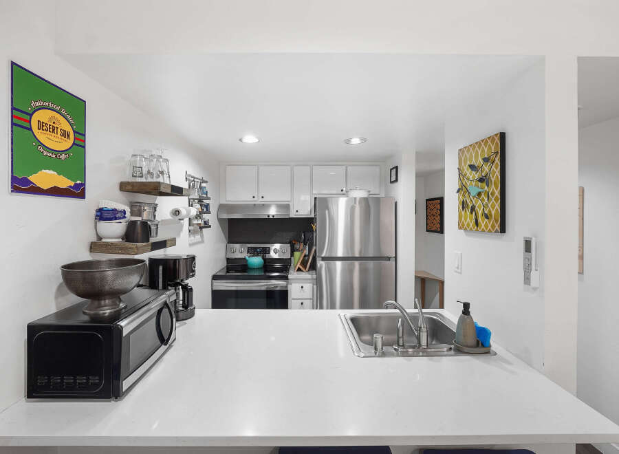 Discover this charming kitchen, perfect for coffee lovers, featuring a 'Desert Sun Coffee Roasters' sign and a convenient coffee maker.