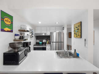 Discover this charming kitchen, perfect for coffee lovers, featuring a 'Desert Sun Coffee Roasters' sign and a convenient coffee maker.