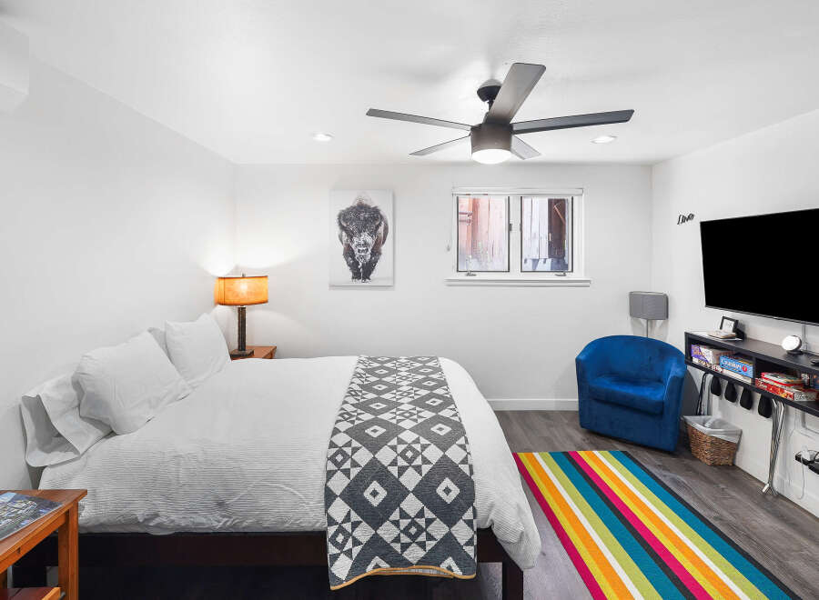 Experience comfort and style in this inviting bedroom, featuring a plush queen-size bed adorned with crisp white linens and a decorative geometric throw.
