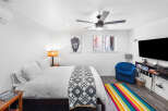 Experience comfort and style in this inviting bedroom, featuring a plush queen-size bed adorned with crisp white linens and a decorative geometric throw.