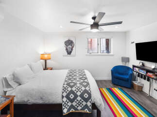 Experience comfort and style in this inviting bedroom, featuring a plush queen-size bed adorned with crisp white linens and a decorative geometric throw.