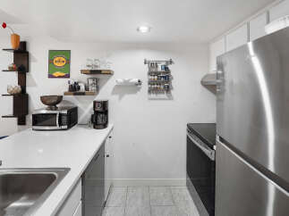 This compact kitchen features a sleek stainless steel refrigerator and a modern black electric stove, perfect for efficient meal preparation.