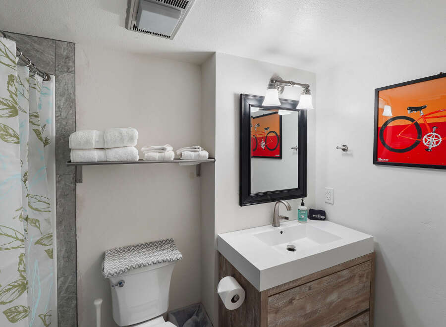 Discover this charming bathroom featuring a modern vanity with a sleek white sink and a rustic wood cabinet.