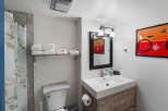 Discover this charming bathroom featuring a modern vanity with a sleek white sink and a rustic wood cabinet.
