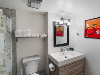 Discover this charming bathroom featuring a modern vanity with a sleek white sink and a rustic wood cabinet.