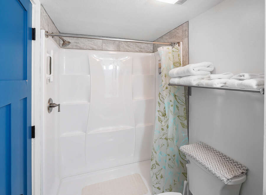 Step into this clean and bright bathroom featuring a spacious white shower stall with a convenient handheld showerhead.