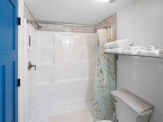 Step into this clean and bright bathroom featuring a spacious white shower stall with a convenient handheld showerhead.