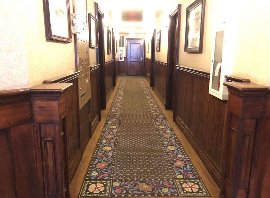Step into this charming hallway featuring rich wood paneling and a beautifully patterned runner carpet.