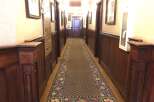Step into this charming hallway featuring rich wood paneling and a beautifully patterned runner carpet.