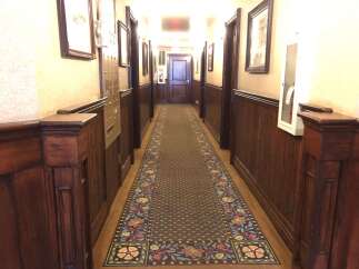 Step into this charming hallway featuring rich wood paneling and a beautifully patterned runner carpet.
