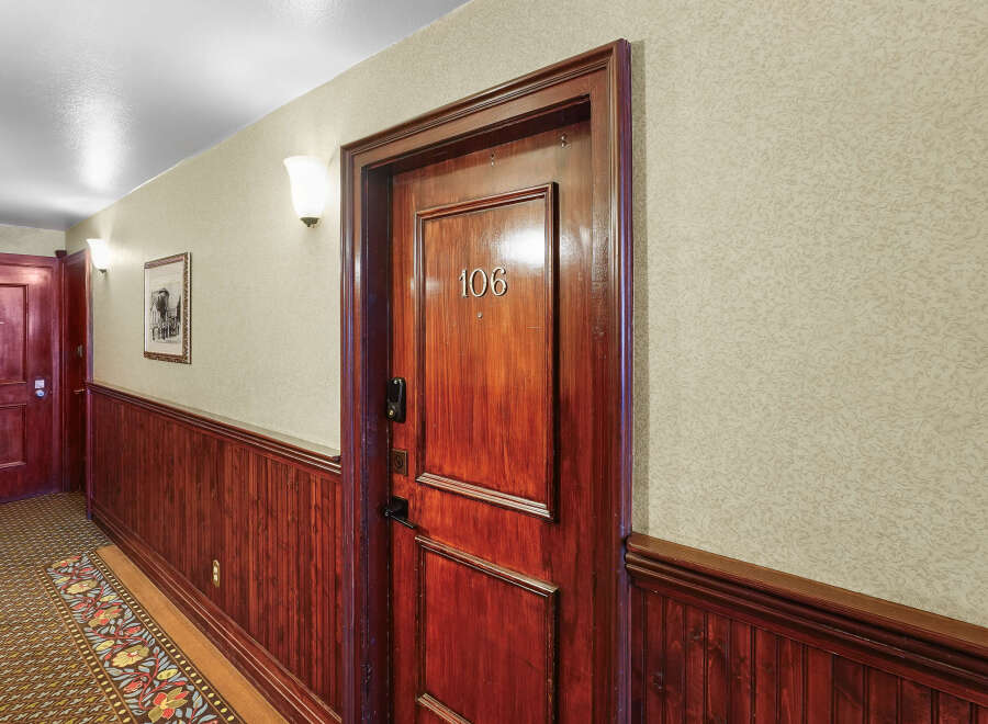 Step into this charming hallway featuring a beautifully crafted wooden door with the number 106 prominently displayed.