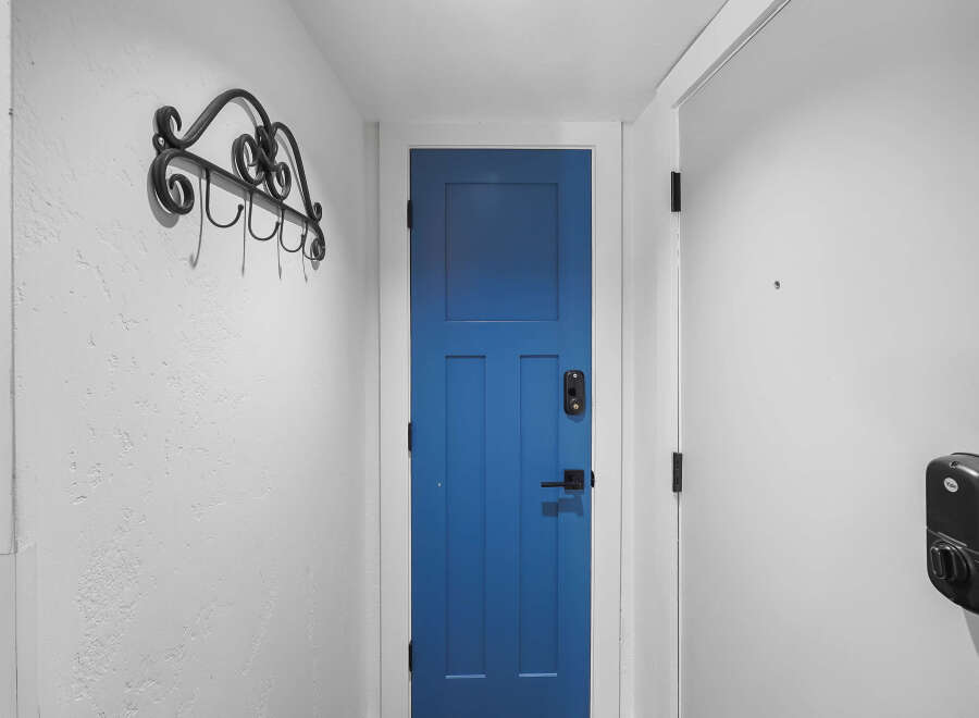 Enhance your home's security and style with this modern entryway featuring a vibrant blue door and a sleek black smart lock.
