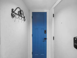 Enhance your home's security and style with this modern entryway featuring a vibrant blue door and a sleek black smart lock.
