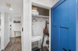 Discover convenient storage solutions with this well-organized closet, featuring a vacuum cleaner, broom, and ironing board.