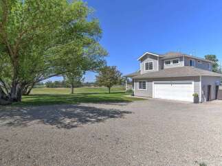 Discover this charming two-story home featuring a spacious gravel driveway leading to an attached two-car garage.