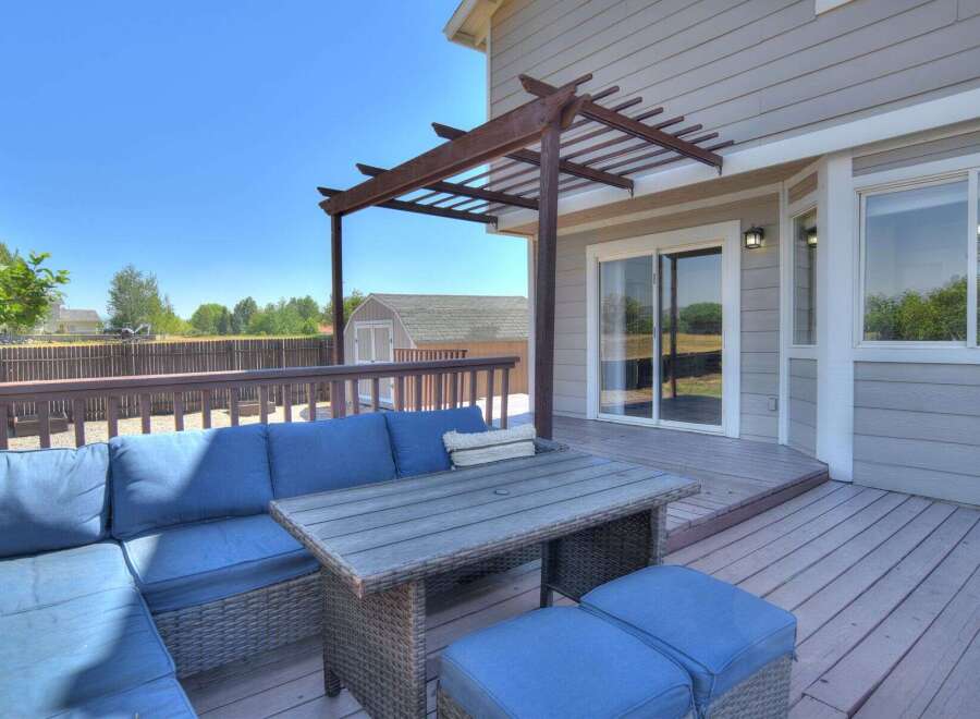 Enjoy outdoor living on this spacious deck, complete with a comfortable sectional sofa and a dining table perfect for al fresco meals.
