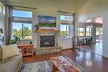 Experience breathtaking mountain views from this stunning living room, featuring a grand stone fireplace and a large picture window.