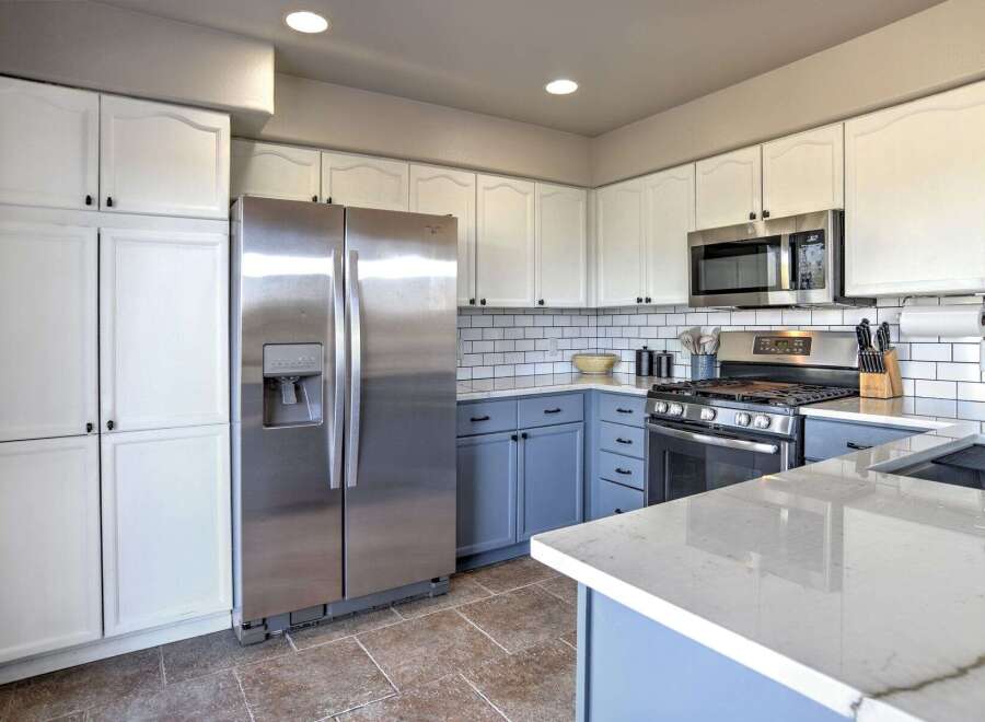 This kitchen boasts a modern aesthetic with crisp white upper cabinets contrasting beautifully with the serene blue lower cabinets.