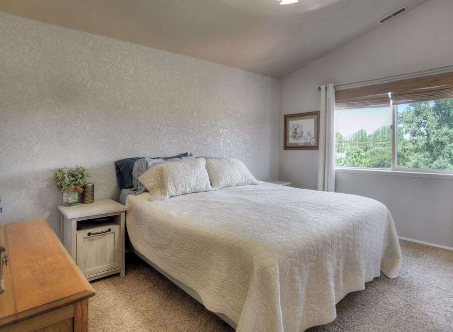 This charming bedroom features a comfortable queen-size bed adorned with a textured white quilt and plush pillows.