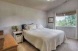 This charming bedroom features a comfortable queen-size bed adorned with a textured white quilt and plush pillows.