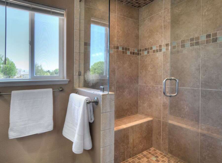 Experience luxury in this beautifully tiled walk-in shower, featuring a built-in bench and a sleek glass door.