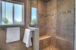 Experience luxury in this beautifully tiled walk-in shower, featuring a built-in bench and a sleek glass door.