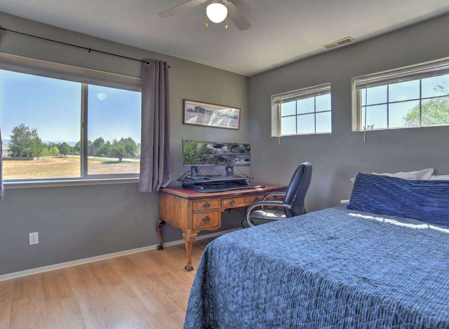 This bedroom offers a dedicated workspace with a vintage wooden desk and an ergonomic chair, perfect for remote work or study.