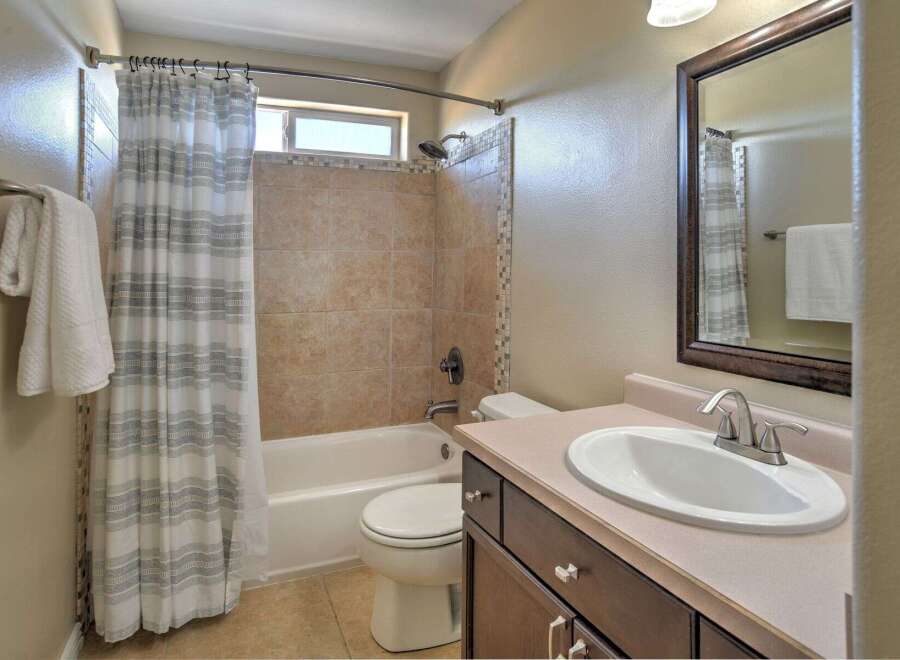 This bathroom features a bathtub/shower combo with tiled walls and a decorative mosaic tile accent.