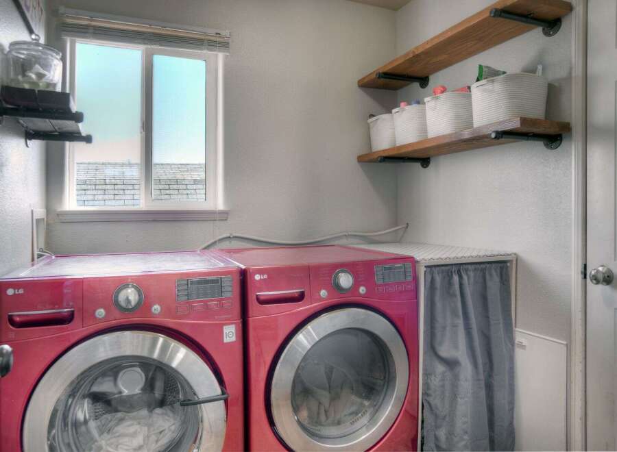 This laundry room features a pair of vibrant red LG front-load washers, offering ample capacity for your laundry needs.