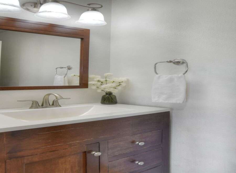 This bathroom features a stylish dark wood vanity with silver hardware, complemented by a white countertop and sink.
