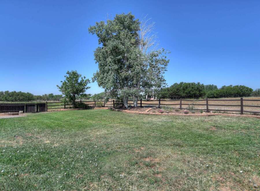 Enjoy the expansive backyard with a mature tree providing shade and a rustic wooden fence enclosing the property.