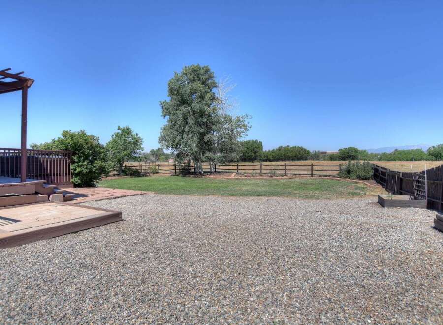 Enjoy outdoor living with this spacious backyard featuring a large wooden deck and pergola, perfect for entertaining.