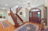 Step into a grand foyer featuring a beautiful wooden staircase with a patterned runner and a large oriental rug.