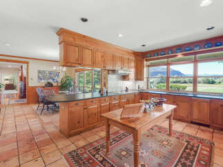 This spacious kitchen boasts custom wood cabinetry and a large island, perfect for meal preparation and casual dining.
