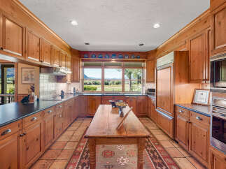 Experience the charm of this spacious kitchen, featuring warm wooden cabinetry and a large central island perfect for meal preparation and gathering.