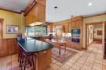 Experience rustic charm in this spacious kitchen featuring warm wood cabinetry and a large island with a dark countertop, perfect for casual dining.