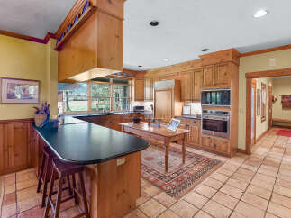 Experience rustic charm in this spacious kitchen featuring warm wood cabinetry and a large island with a dark countertop, perfect for casual dining.